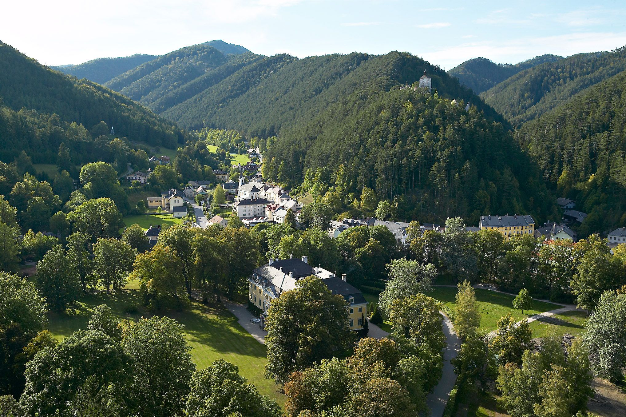 Letecký pohľad na Gutenstein so zelenými kopcami a hradom na kopci.