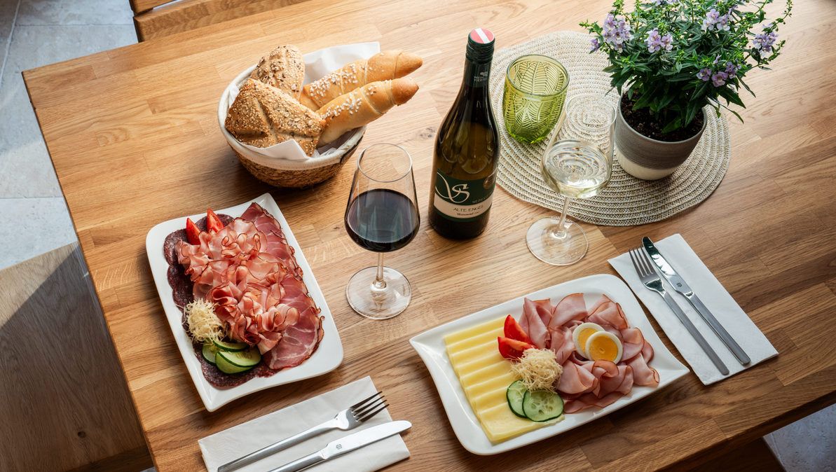 Stôl s regionálnymi pochúťkami: Chladené nárezy, syry, chlieb, červené a biele víno.