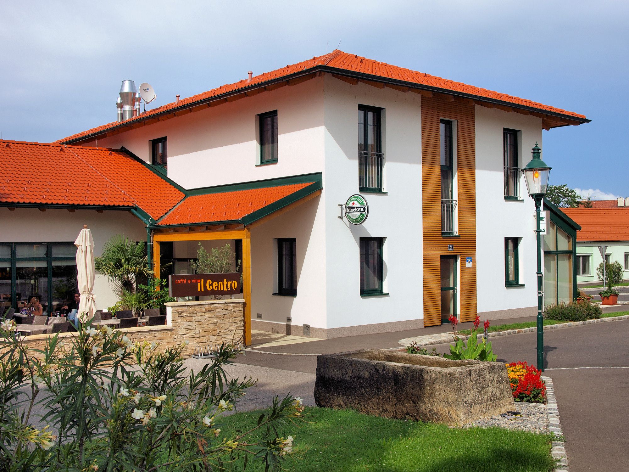 Pohľad zvonku na budovu s červenou strechou a terasou s nápisom "caffè e vini Centro".