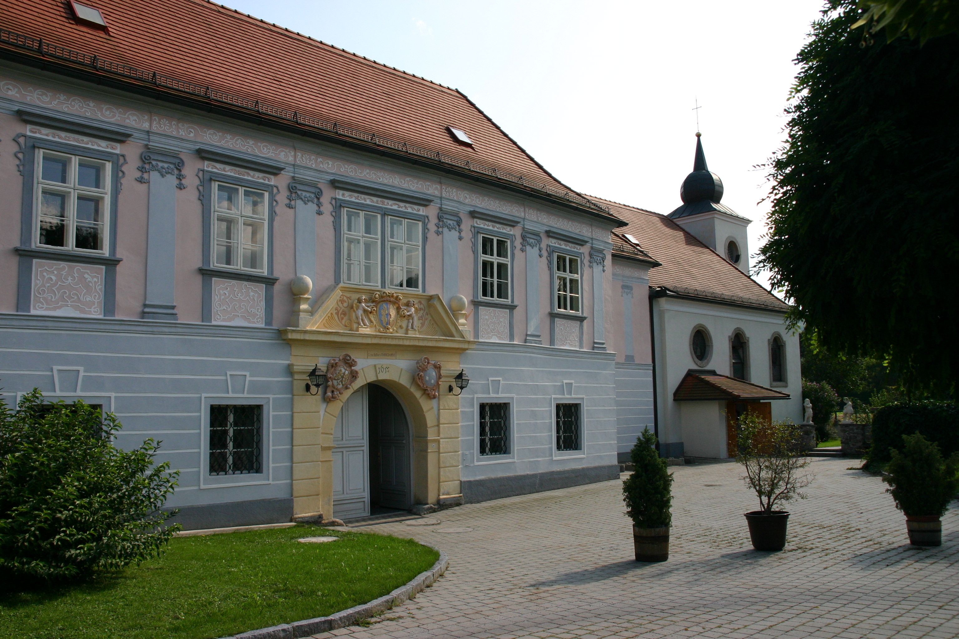 Historická budova so zdobeným vchodom a kostolom v pozadí.