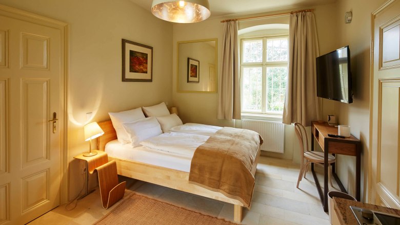 &Uacute;tuln&aacute; sp&aacute;lňa s manželskou posteľou, p&iacute;sac&iacute;m stolom a veľk&yacute;m oknom.