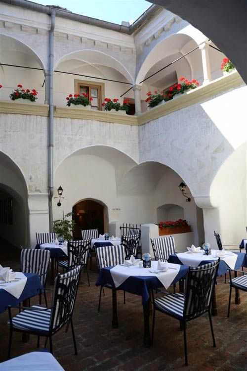 Vnútorné nádvorie hostinca s prestretými stolmi a kvetmi.