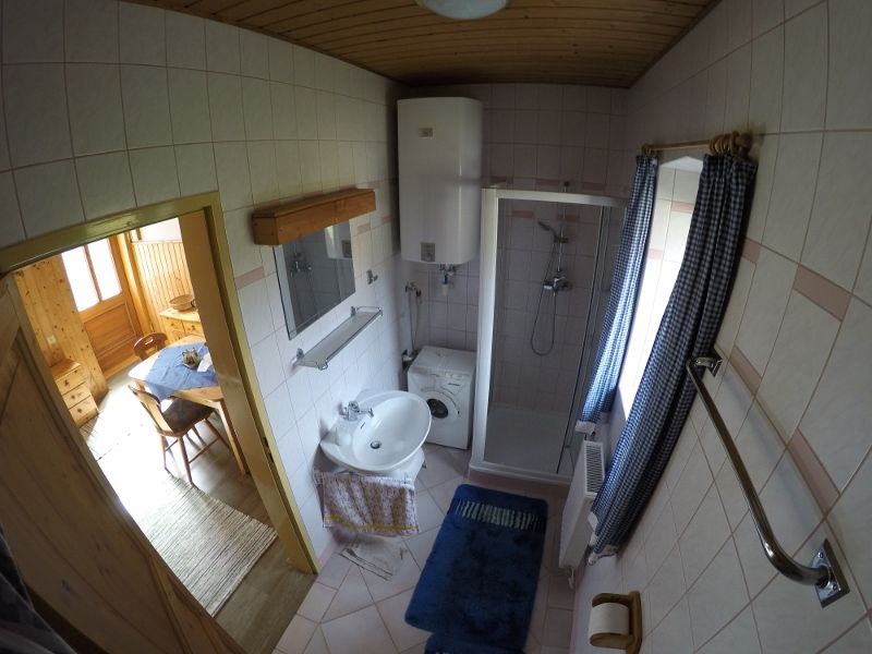 Kúpeľňa so sprchovacím kútom, umývadlom, práčkou a modrými závesmi.