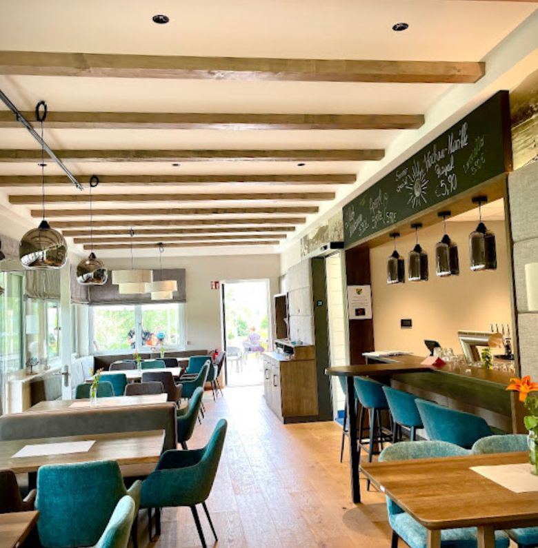 Reštauračná časť vo vnútri so stolmi a zelenými kreslami