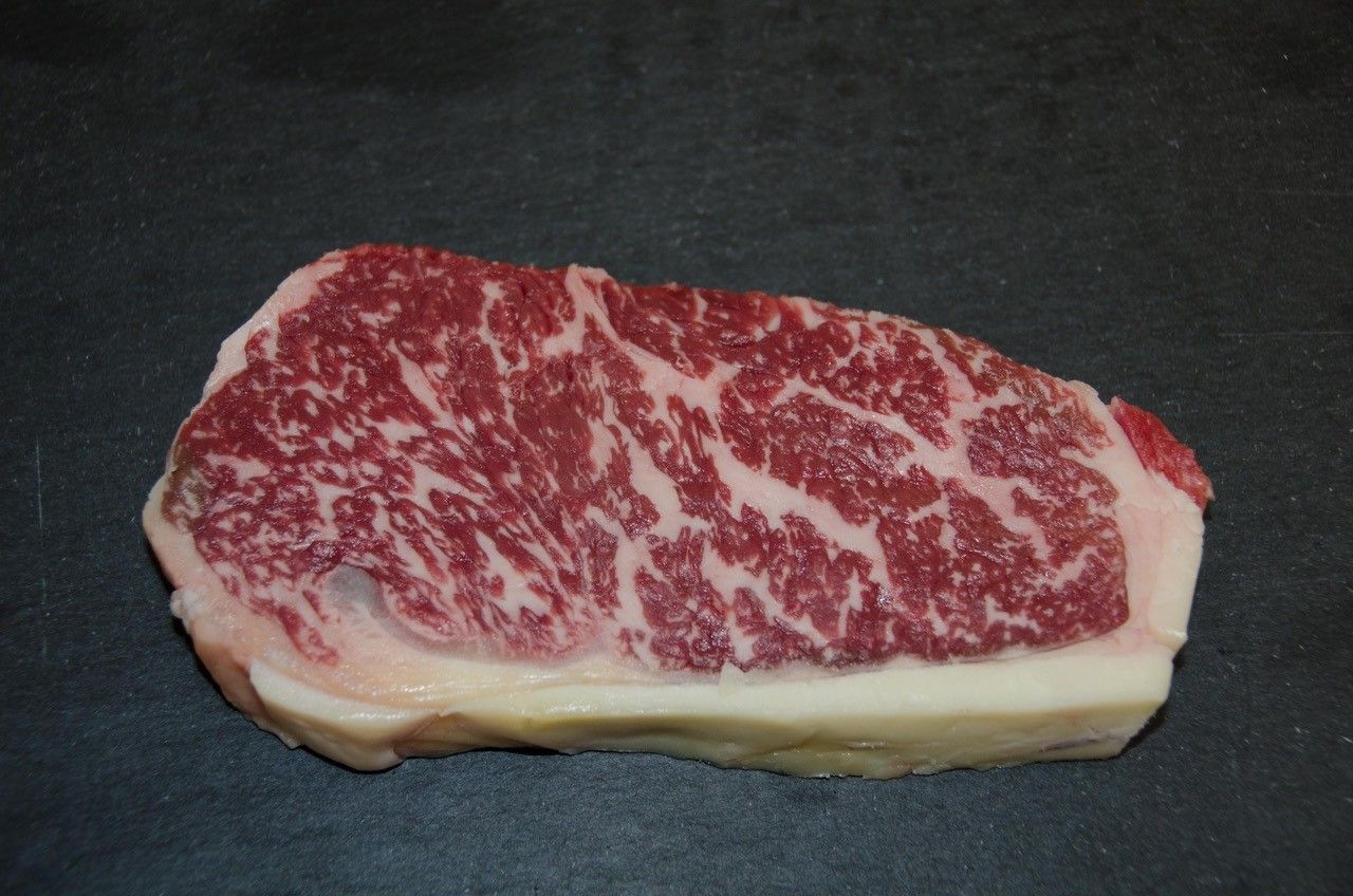 Kus hovädzieho mäsa Wagyu s výrazným mramorovaním na čiernom pozadí.