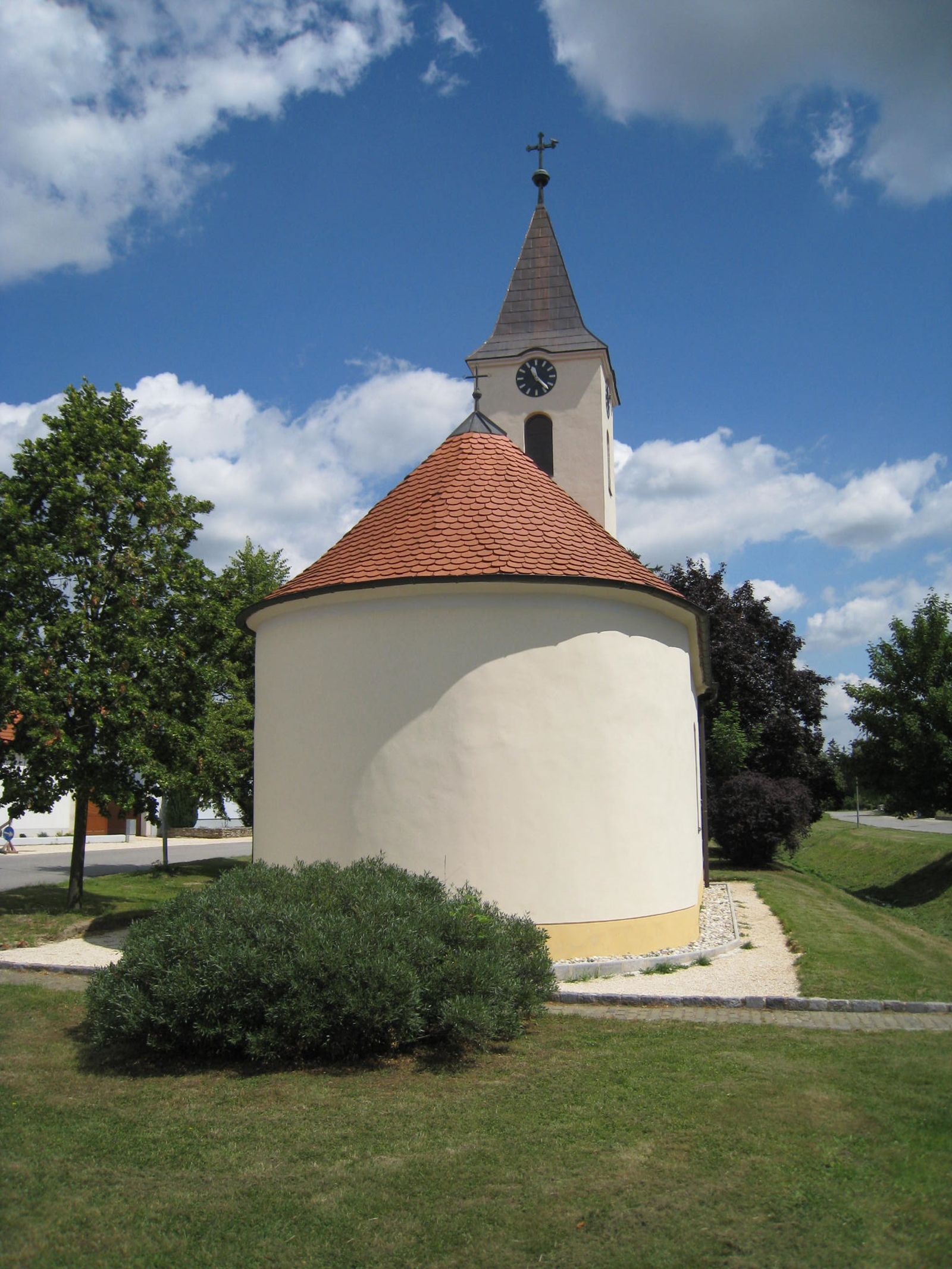 Kaplnka svätej Barbory s okrúhlou strechou a vežou na pozadí modrej oblohy.