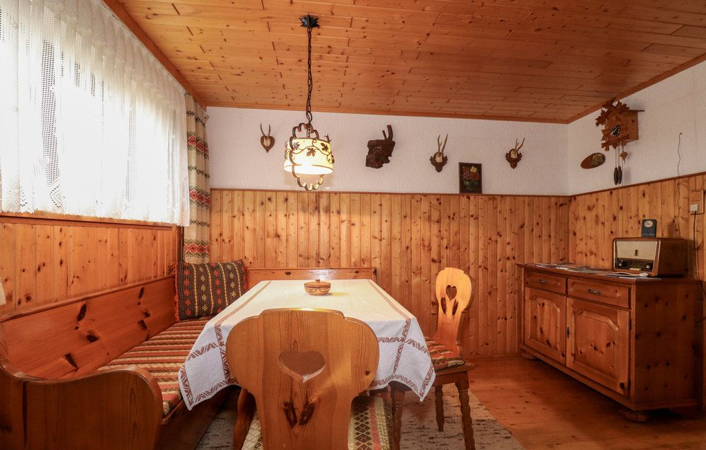Útulný pivničný salónik s dreveným nábytkom, rohovou lavicou, stolom, rádiom a poľovníckymi trofejami na stene.