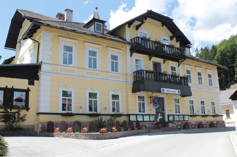 Žltá budova s balkónom a kvetinovými truhlíky, Land-Pension Kaiserhof.