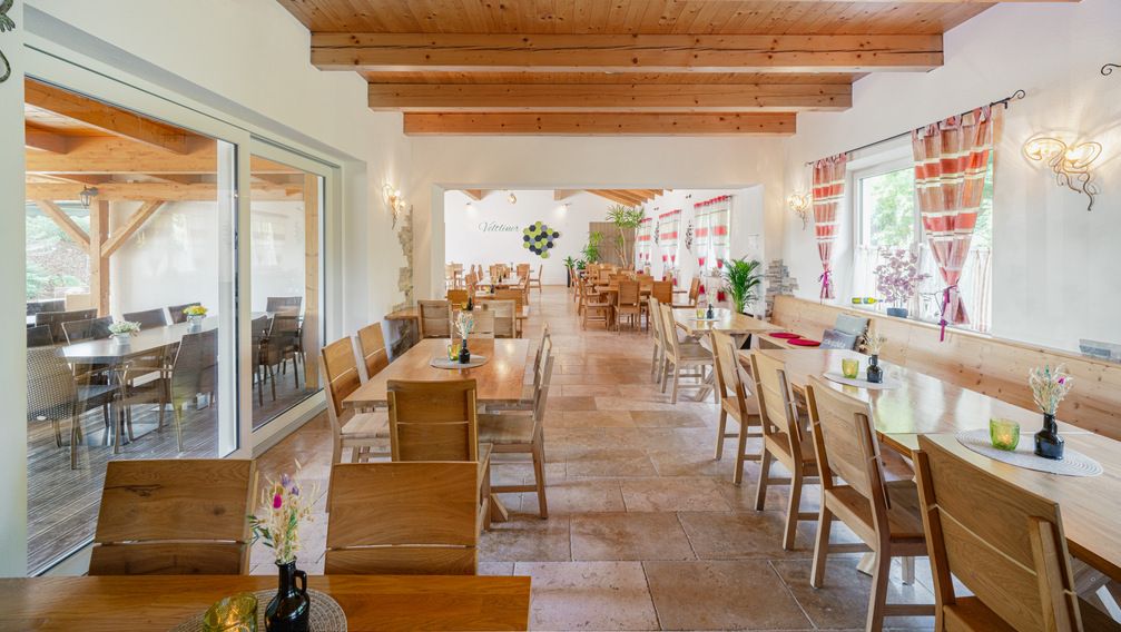 Pohľad do interiéru útulnej vinárne s dreveným nábytkom a ozdobnými závesmi.