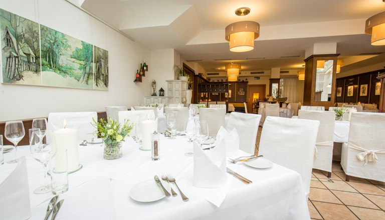 Der Wintergarten mit einem gedeckten Tisch und weißen Stühlen.