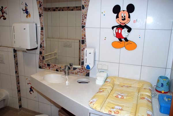 Detská kúpeľňa s dekorom Mickey Mouse a prebaľovacím pultom.