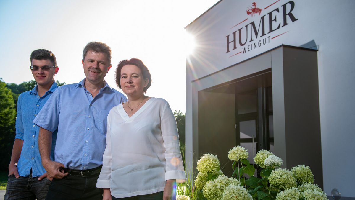 Traja ľudia pred vchodom do vinárstva Humer obklopení kvetmi.