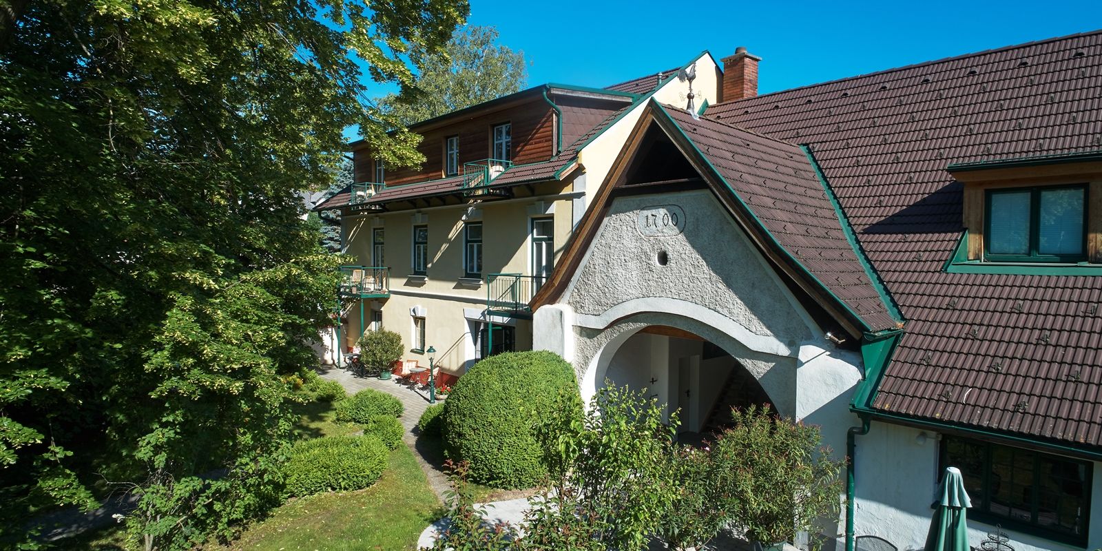 Landhaus Puchbergerhof so záhradou a stromami v popredí.