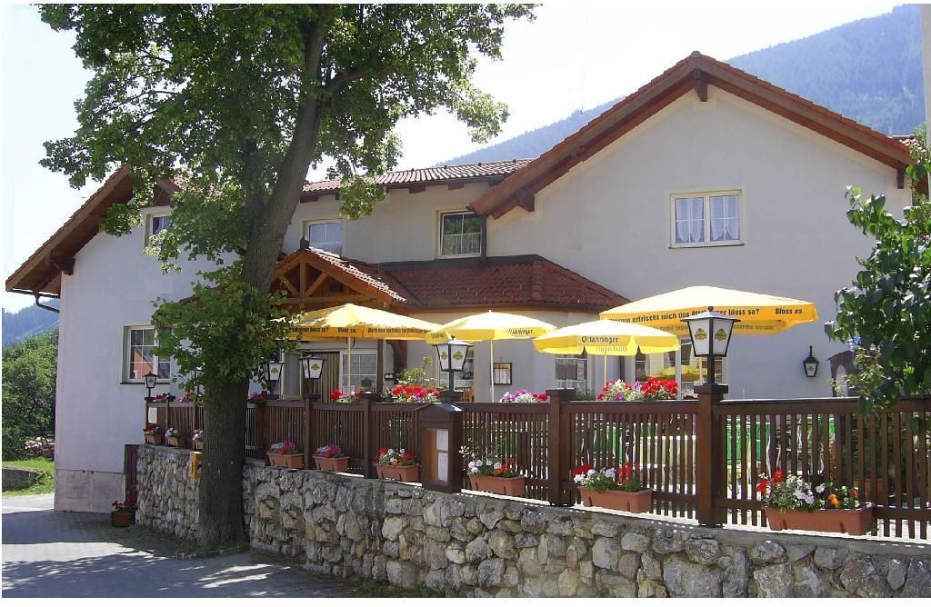 Hostinec s terasou a žltými slnečníkmi.