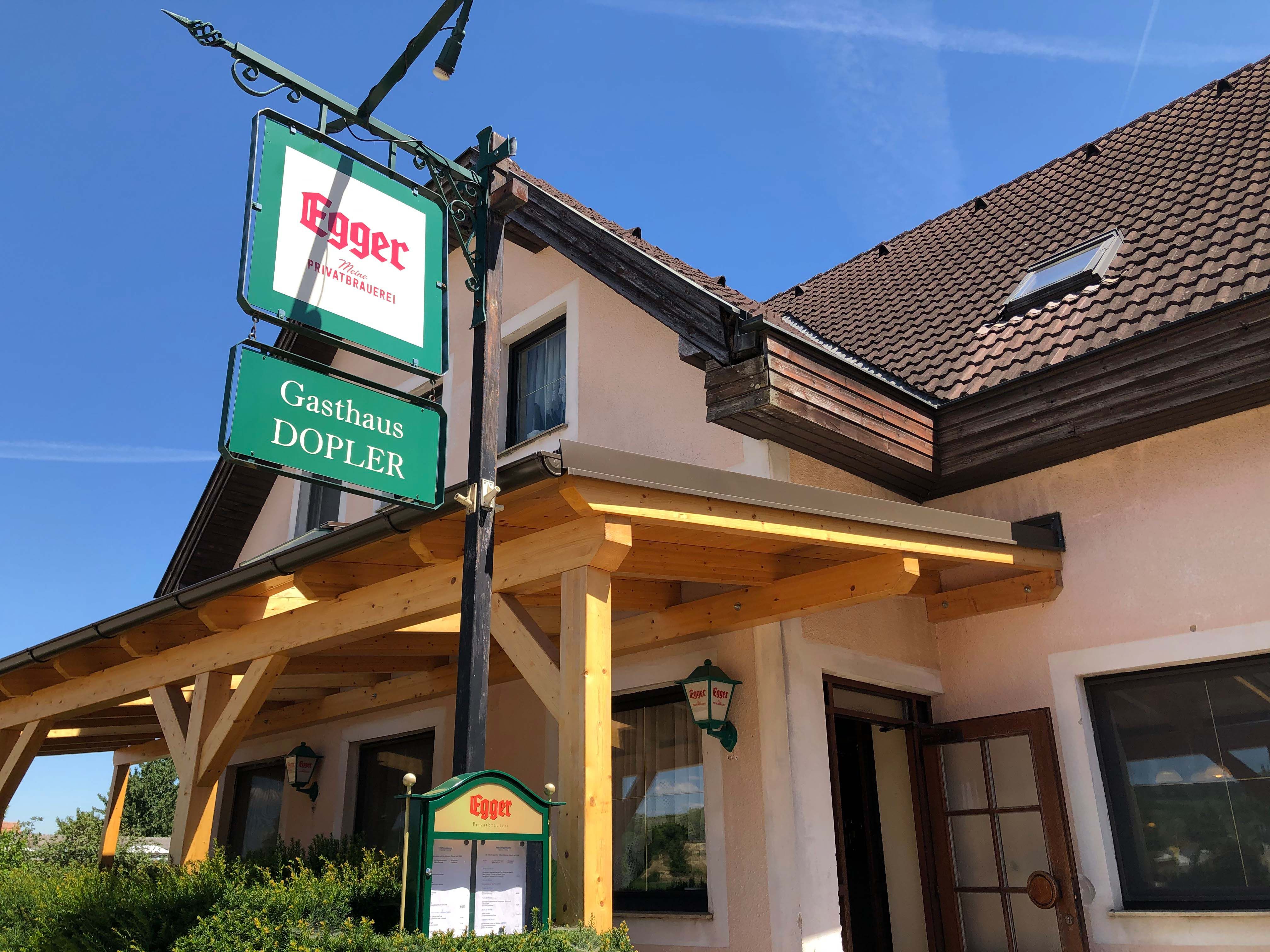 Gasthaus Doppler s nápisom pivovar Egger a drevenou strechou.