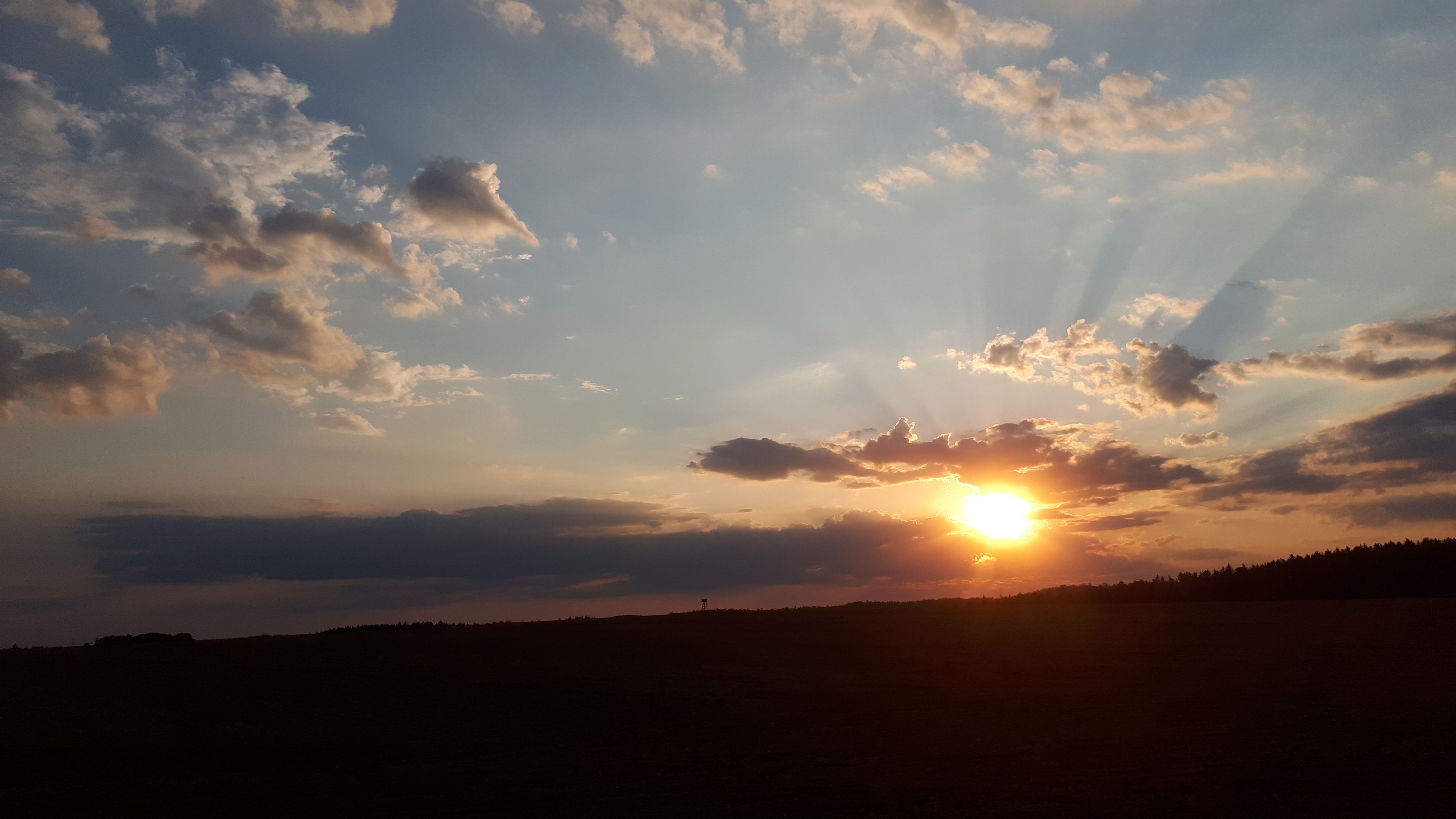 Západ slnka s mrakmi a lúčmi na oblohe.