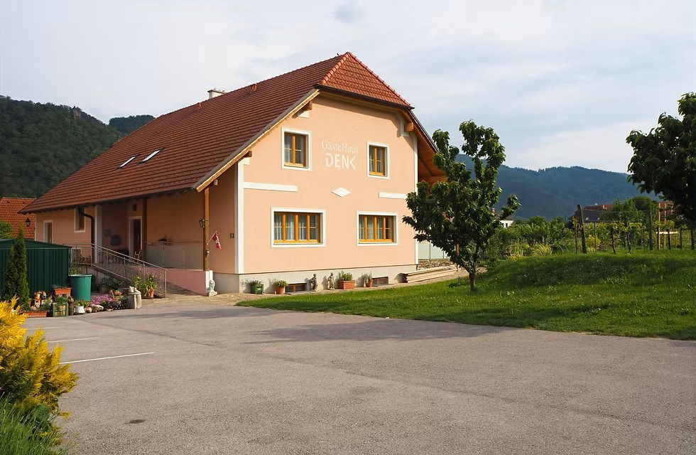 oranžový rodinný dom s asfaltovým parkoviskom pred domom