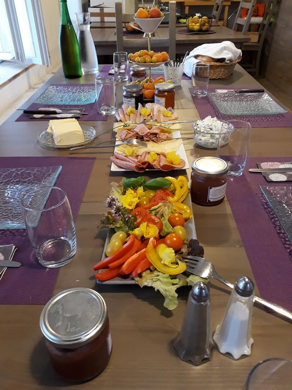 Prestretý raňajkový stôl s údeninami, zeleninou, džemom a nápojmi.