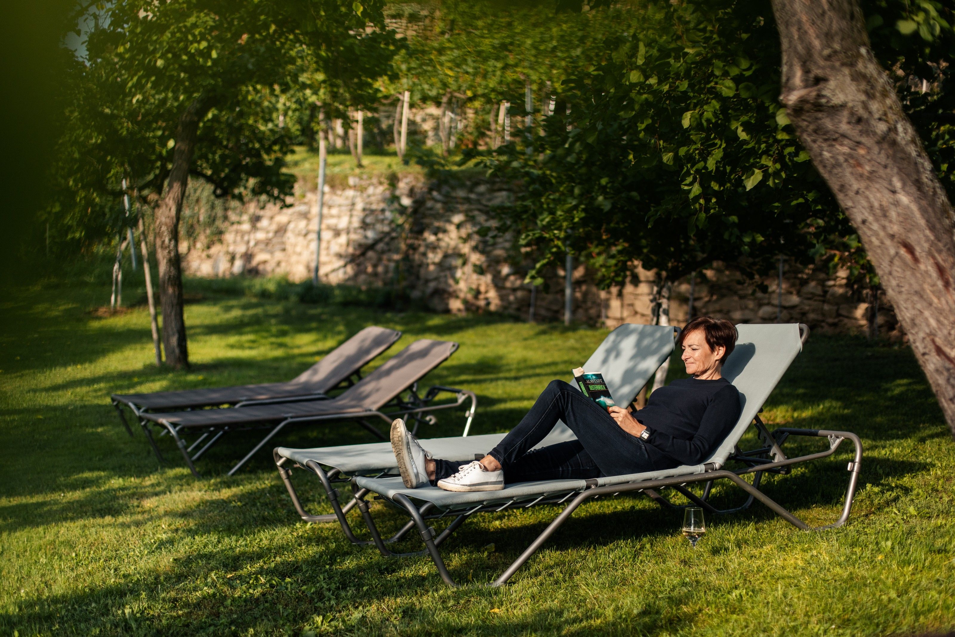 Osoba číta na ležadle v záhrade.