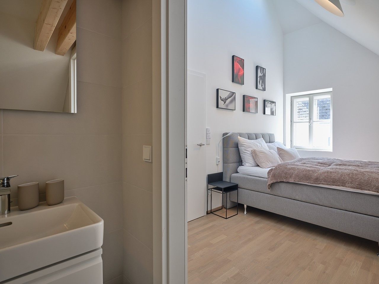 Moderná spálňa so sivou posteľou a priľahlou kúpeľňou.