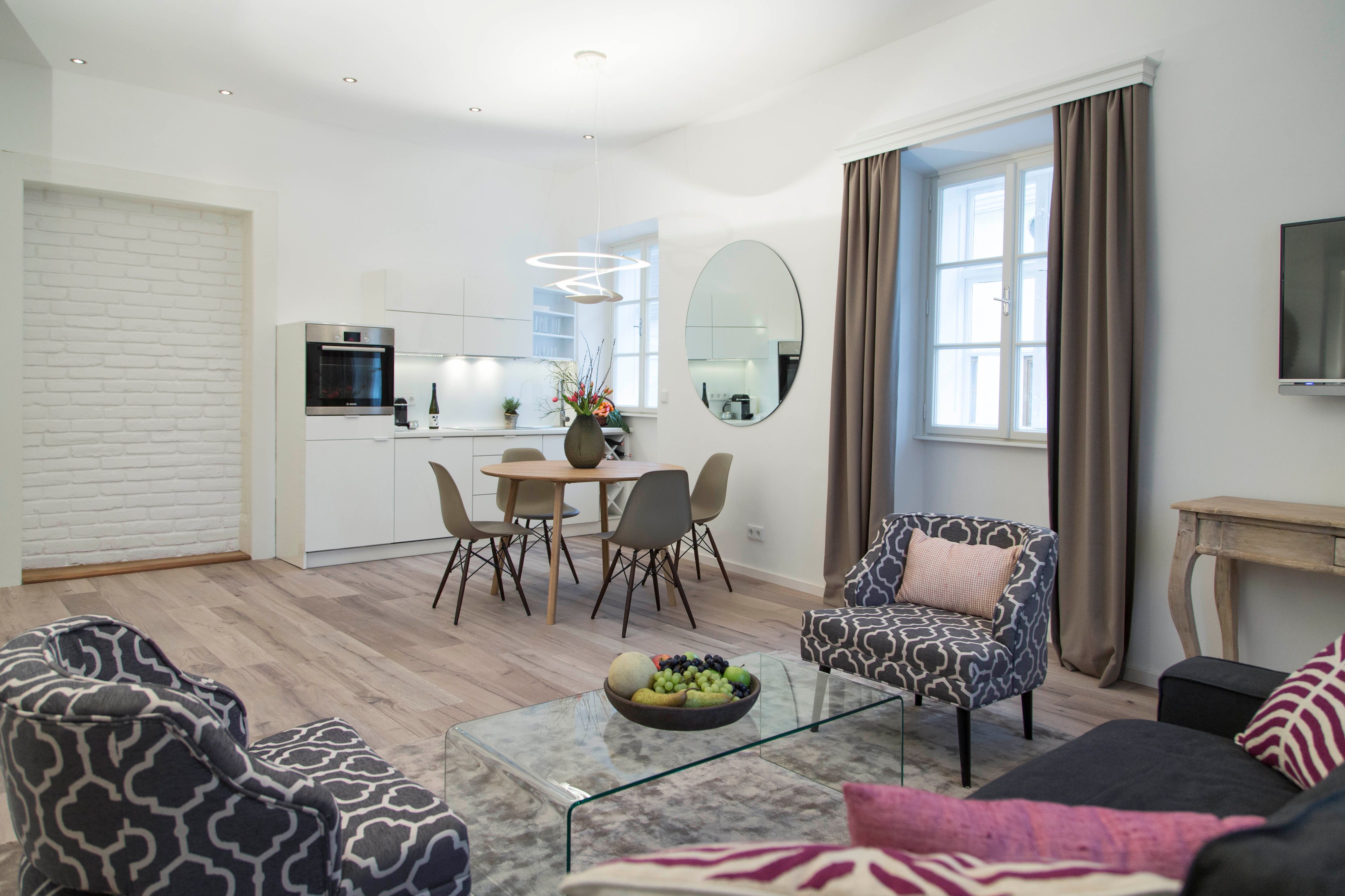 Moderná obývacia izba s kuchyňou, jedálenským stolom a štýlovým nábytkom.