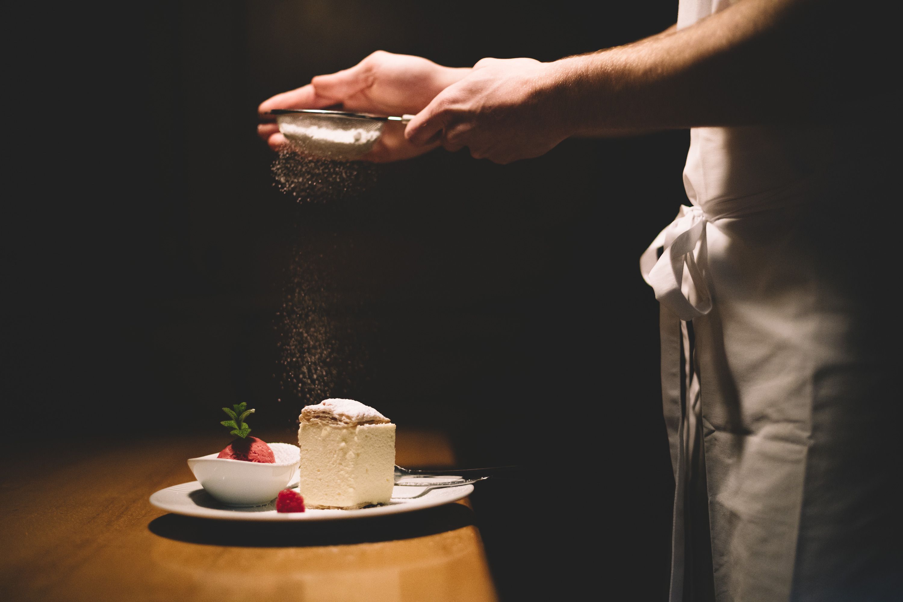 Tanier so šľahačkou a malinovým sorbetom, posypaný práškovým cukrom.