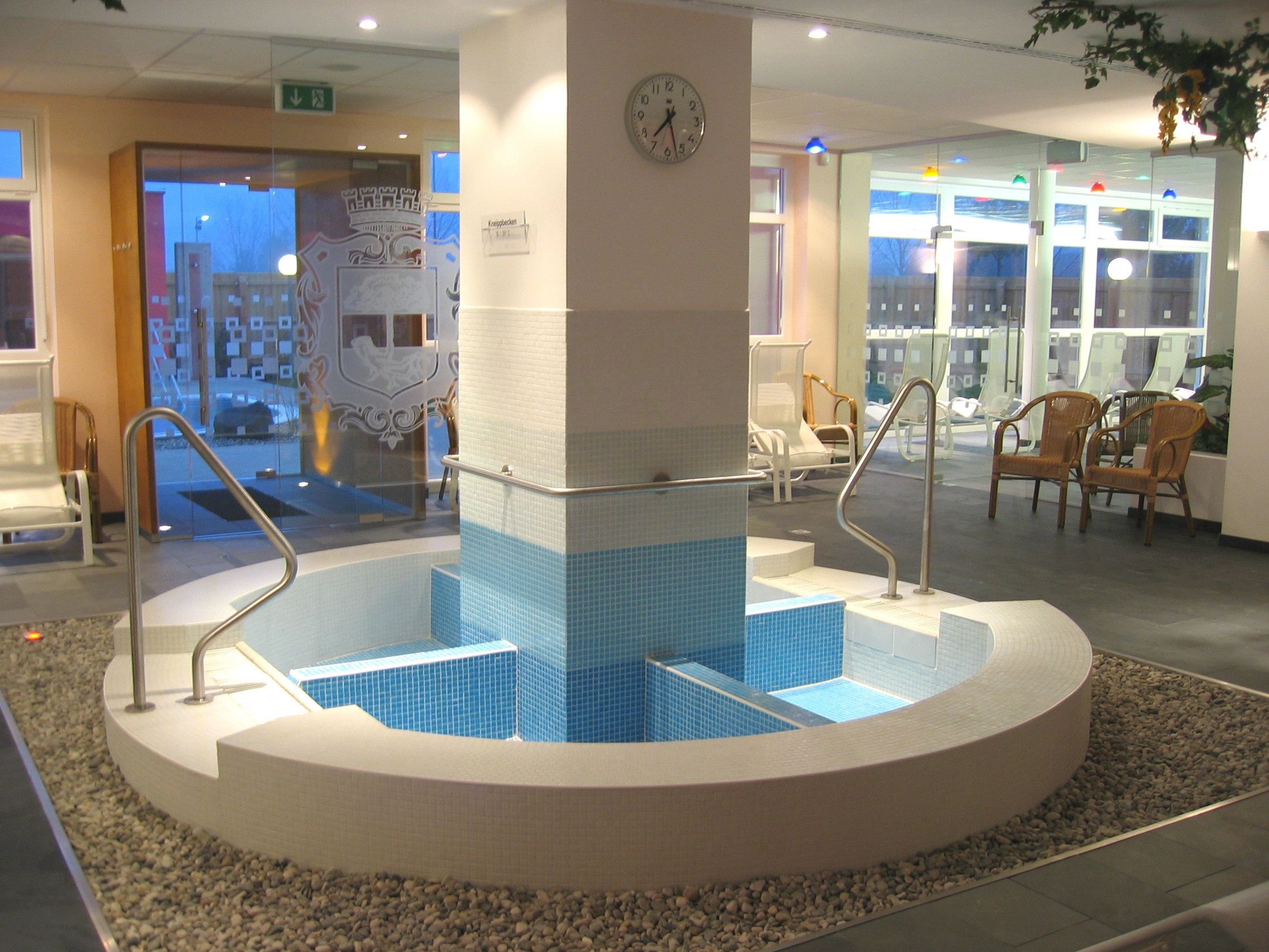 Pohľad do interiéru Kneippovho bazéna v rekreačnom stredisku Stockerau s modrými dlaždicami a zábradlím.