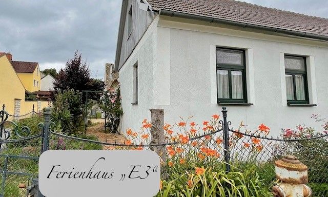 Exteriérový pohľad na biely rekreačný dom so záhradou a kvetmi.