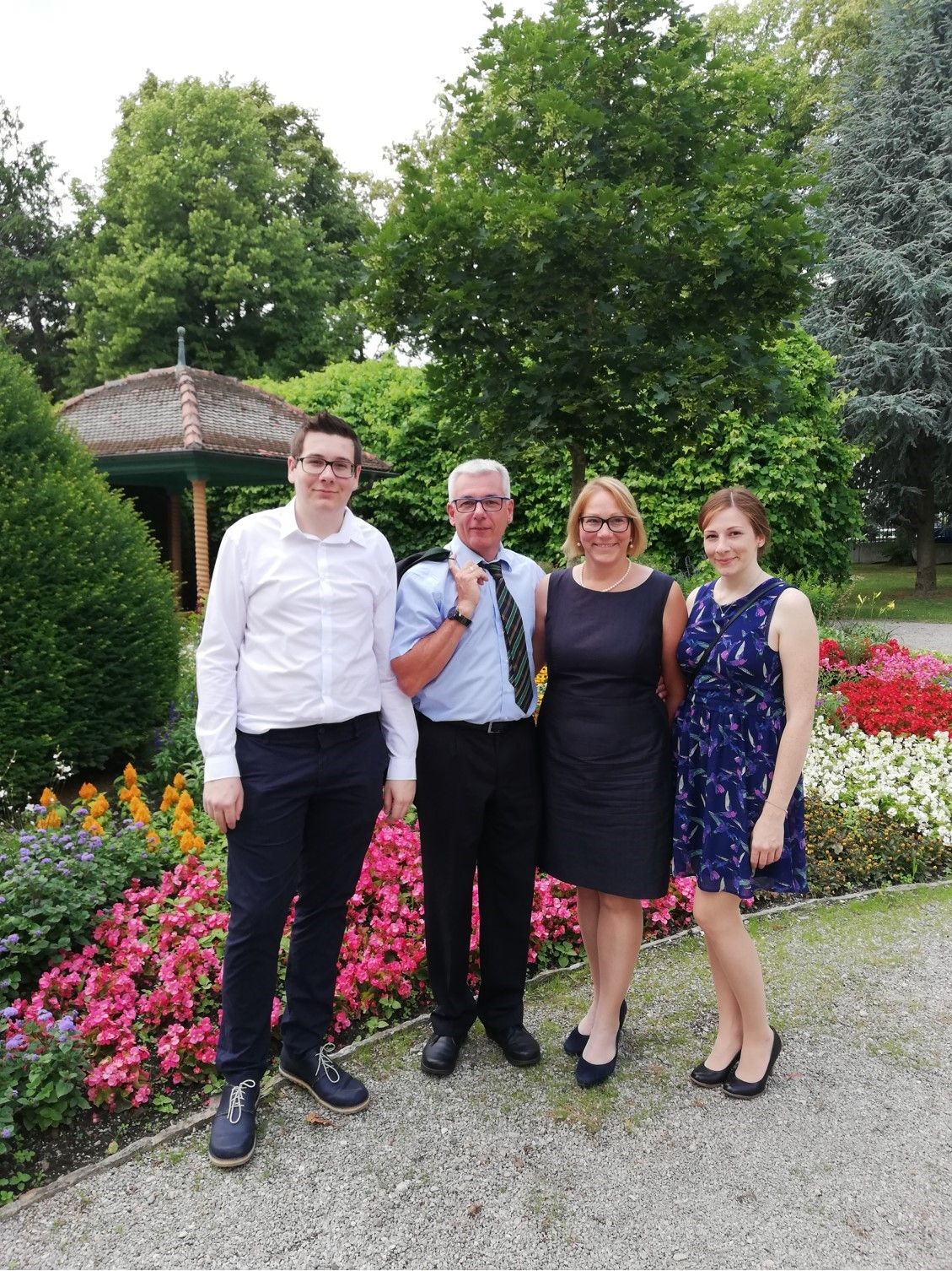 Štyria ľudia stoja pred vonkajším kvetinovým záhonom.