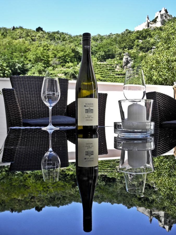 Fľaša vína a poháre na stole s výhľadom na vinice.