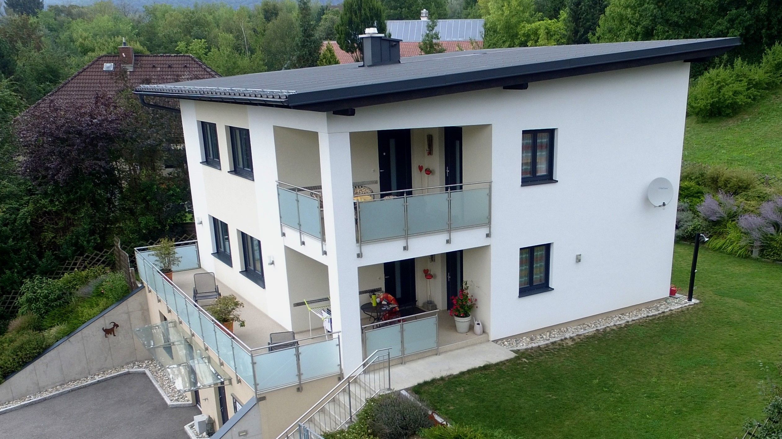 Záber z dronu na moderný dvojpodlažný dom s balkónom a záhradou.