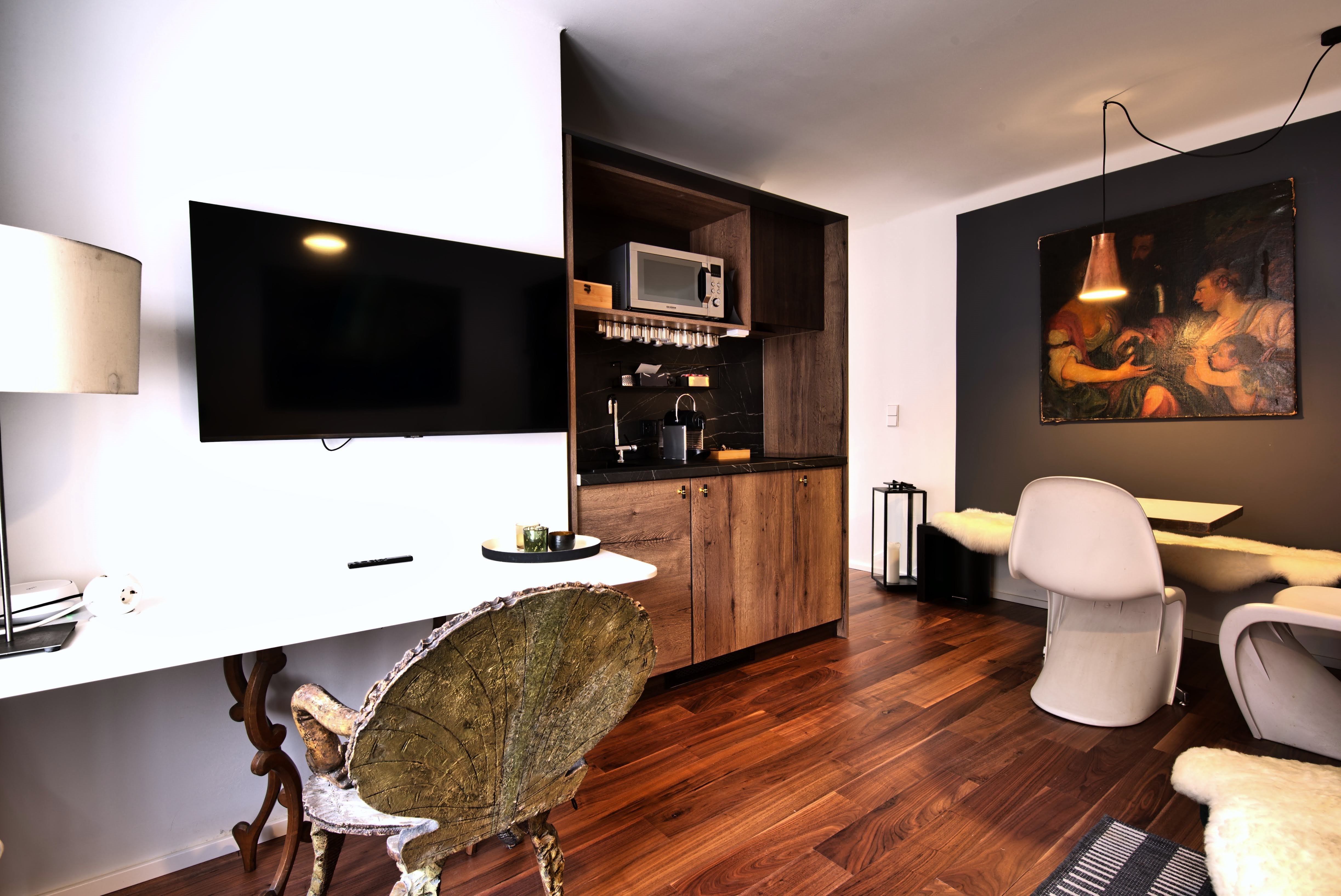 Moderná kuchyňa s drevenými skrinkami, TV s plochou obrazovkou a jedálenským kútom.