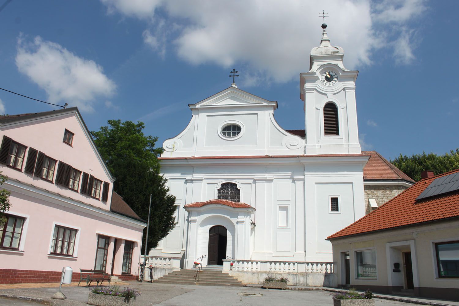 Farský kostol vo Wilfersdorfe s bielou fasádou a zvonicou.