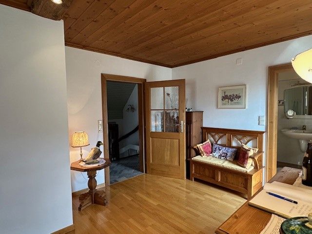 Drevom obložená izba s lavicou, stolnou lampou a otvoreným prístupom do kúpeľne.