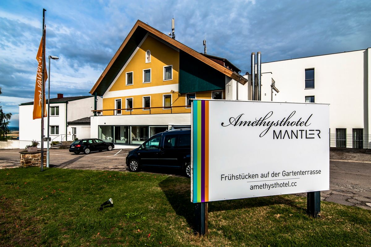 Pohľad na exteriér hotela Amethysthotel Mantler s parkoviskom a nápisom.