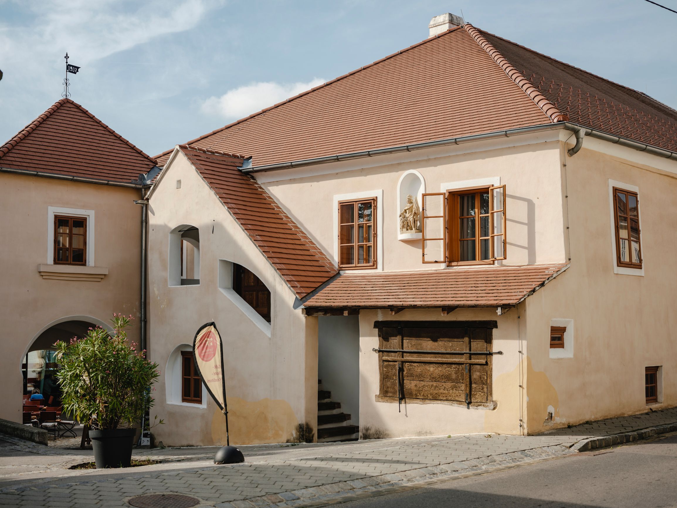 Historická budova s červenými škridlovými strechami a otvorenými oknami.