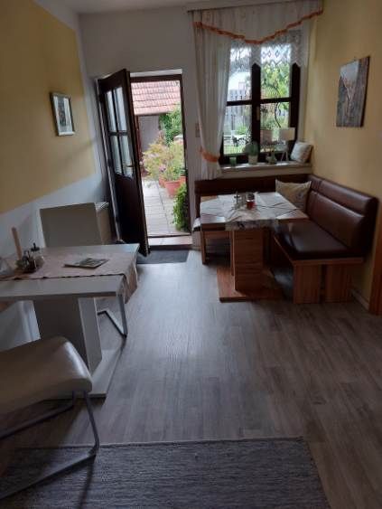Útulná izba pre hostí s jedálenským stolom, stoličkami a lavicou, výhľad na terasu.