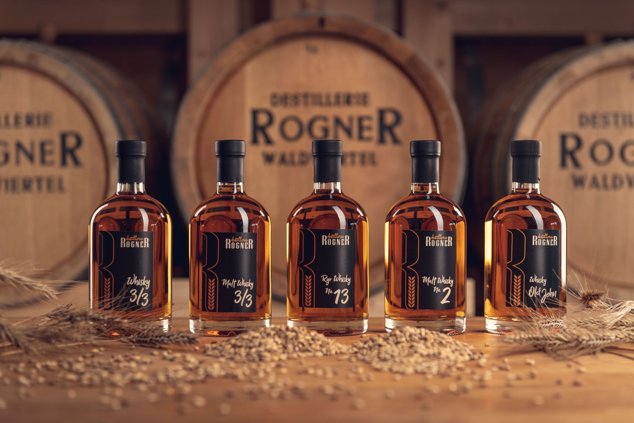 Päť fliaš whisky z liehovaru Rogner pred drevenými sudmi.