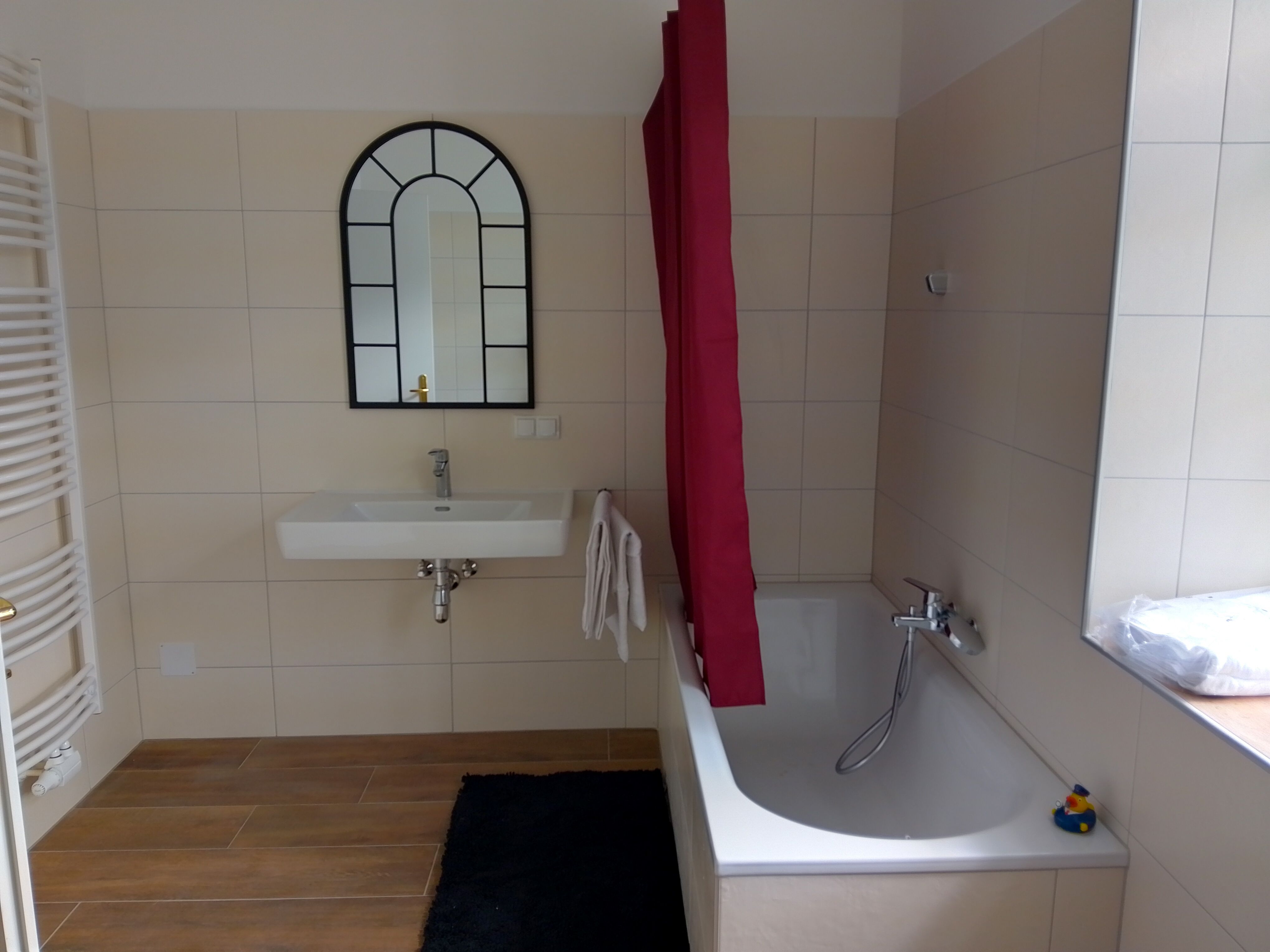 Moderná kúpeľňa s vaňou, umývadlom a zrkadlom.