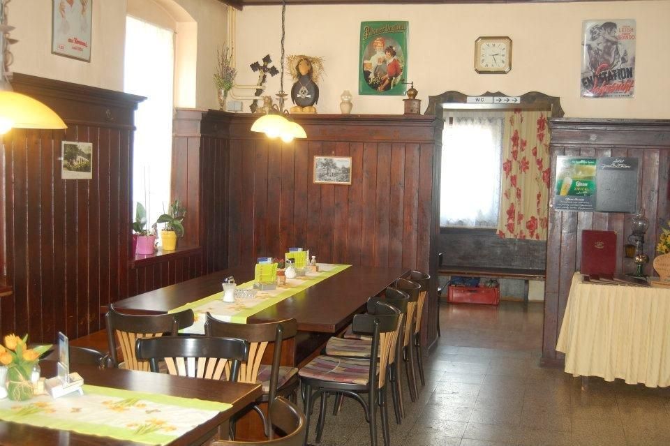 Útulná jedáleň s dreveným obložením, stolom a stoličkami, ozdobnými plagátmi a hodinami na stene.