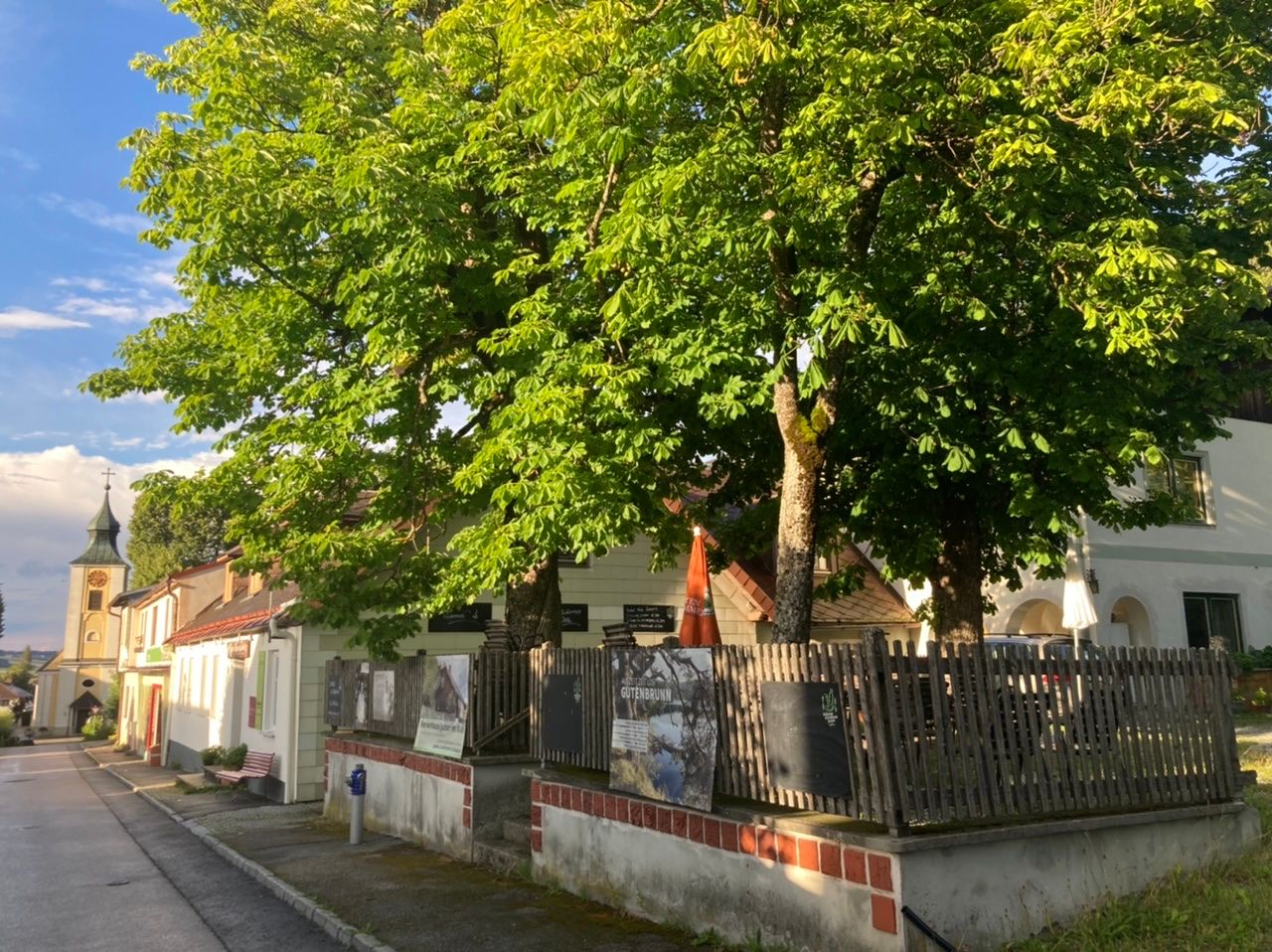 Tradičná krčma s gaštanovou záhradou a kostolom v pozadí.