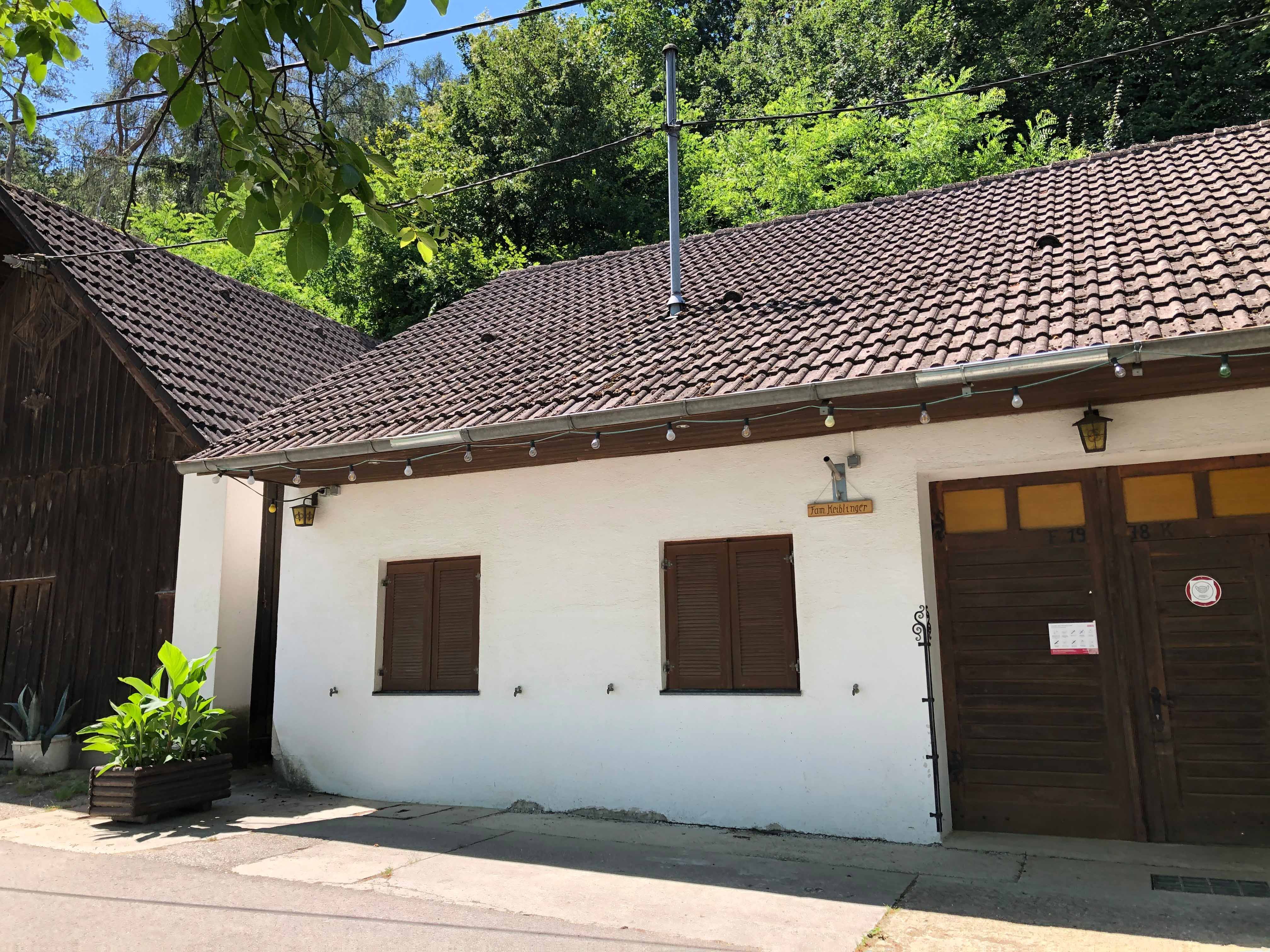 Exteriérový pohľad na vinársku krčmu s bielou fasádou a drevenými dverami.