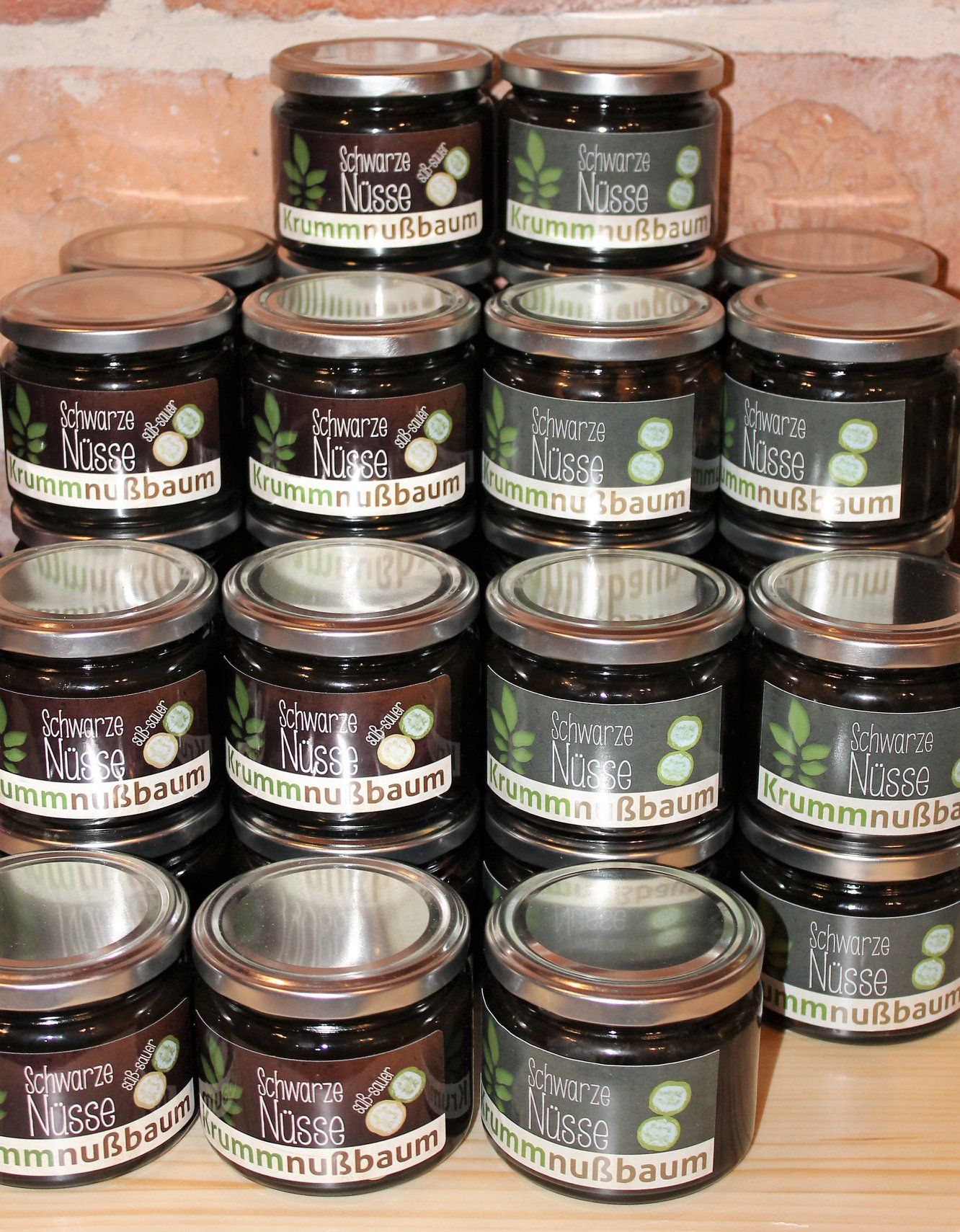 Niekoľko pohárov s nápisom "Schwarze Nüsse Krummnußbaum" poukladaných na stole.