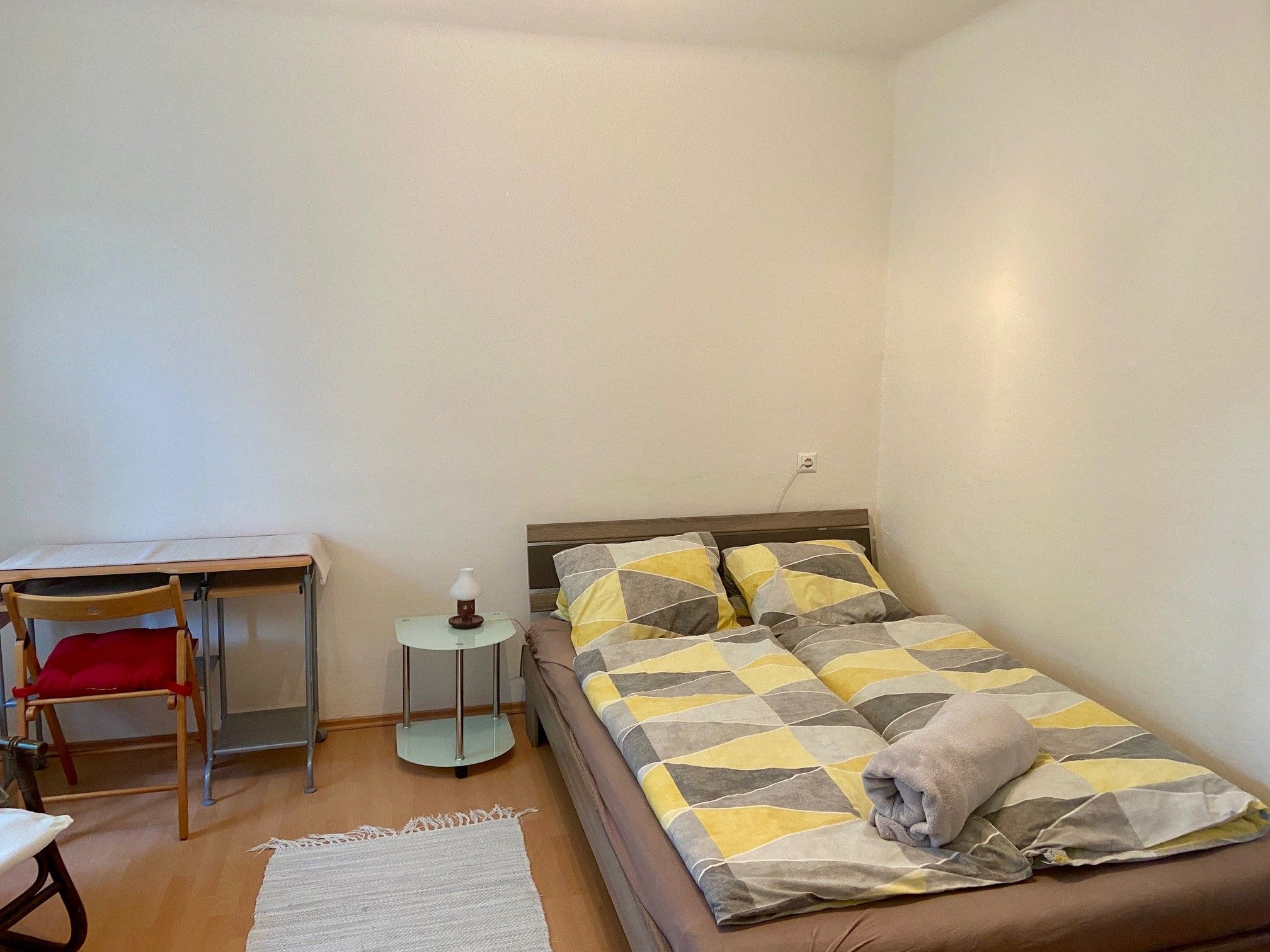 Spálňa s manželskou posteľou, písacím stolom a stoličkou.