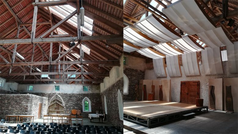 Pohľad do interiéru historickej budovy s drevenou strechou a javiskom.