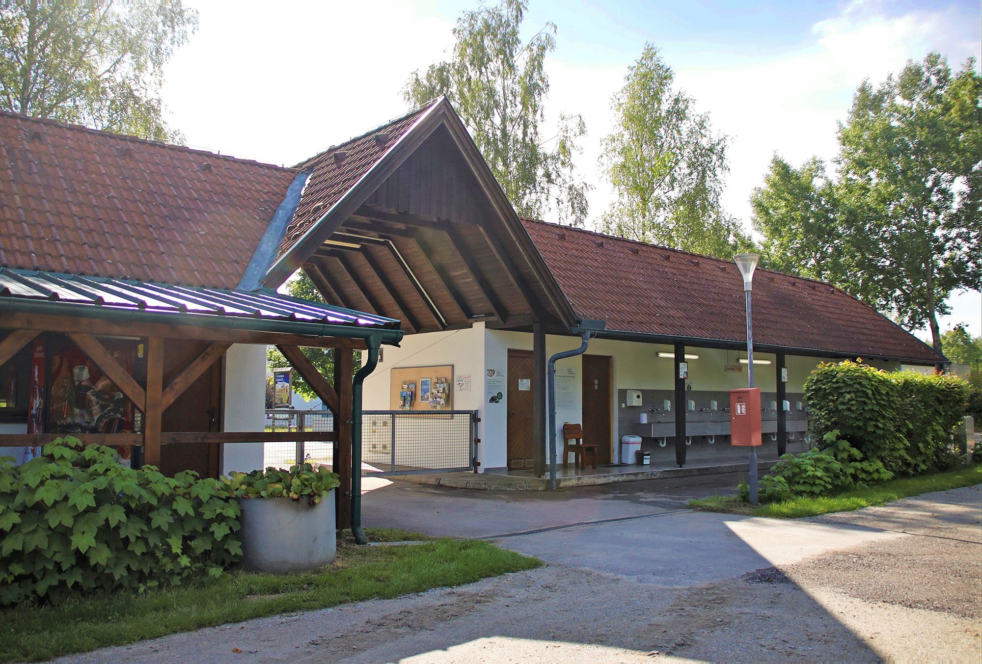 Pohľad zvonku na budovu s červenými škridlovými strechami a vonkajšími umývadlami.