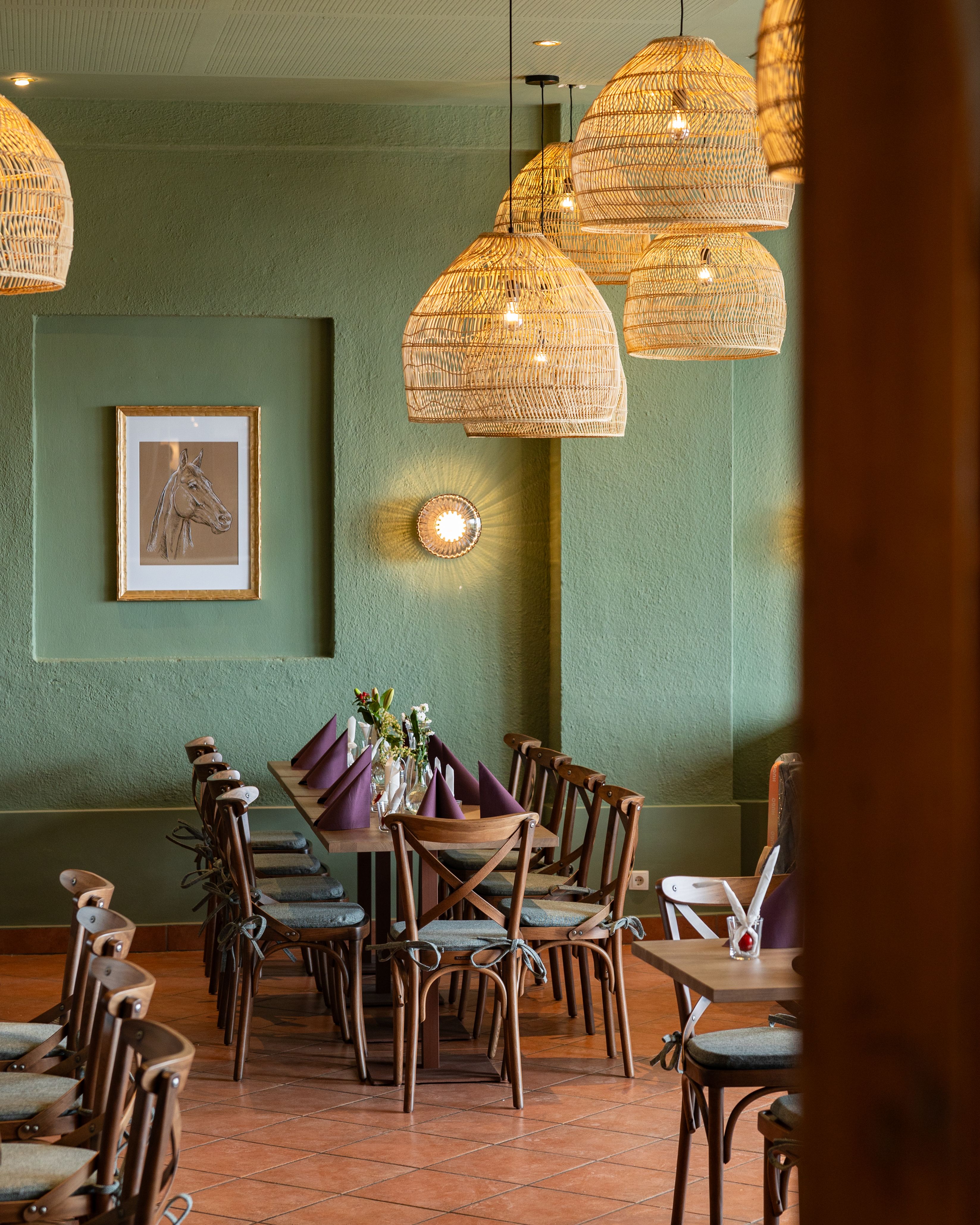 Útulný jedálenský kút s dreveným stolom, stoličkami a tkanými lampami.