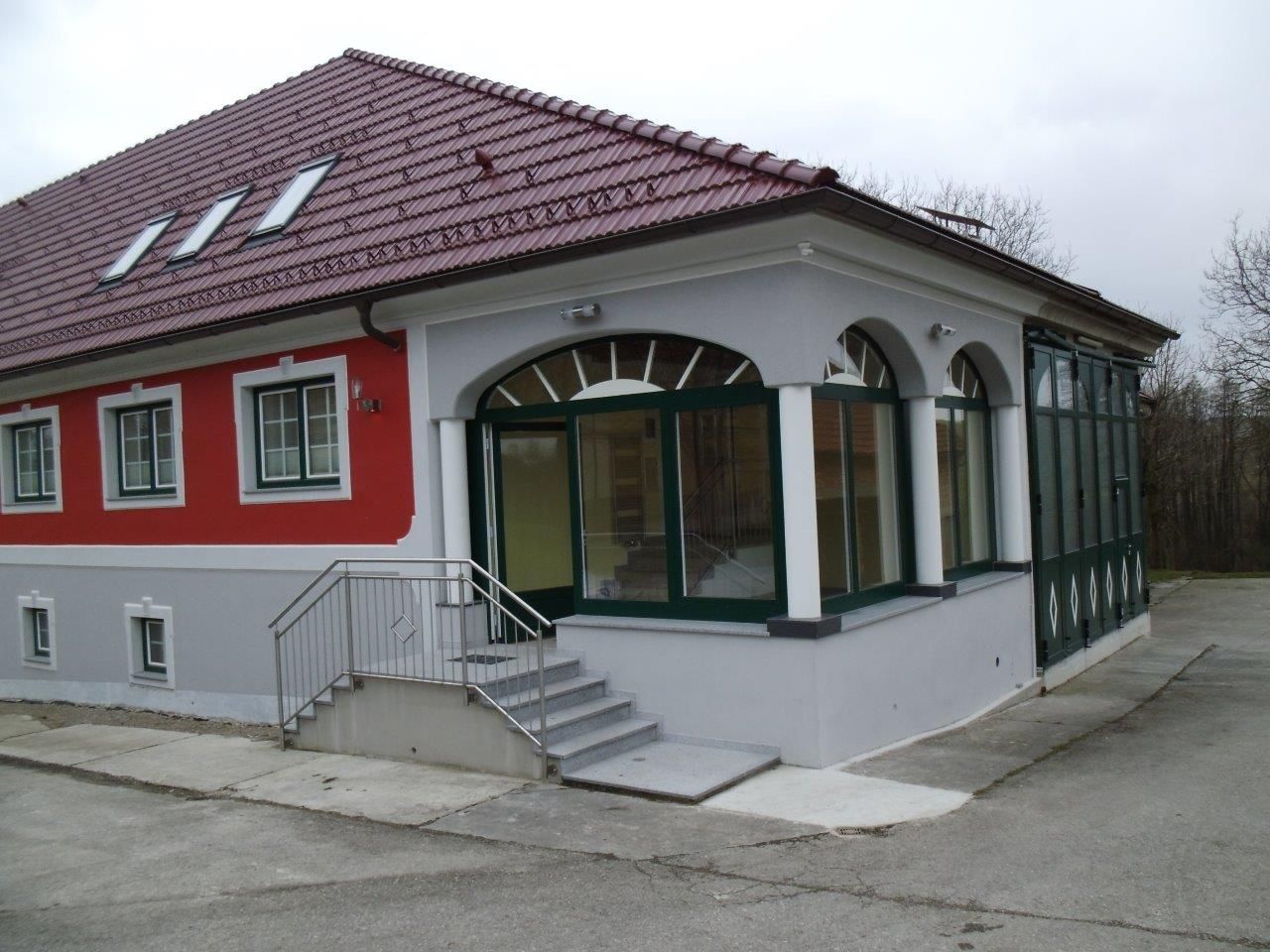 Moderná budova s červenou strechou a červenou fasádou.
