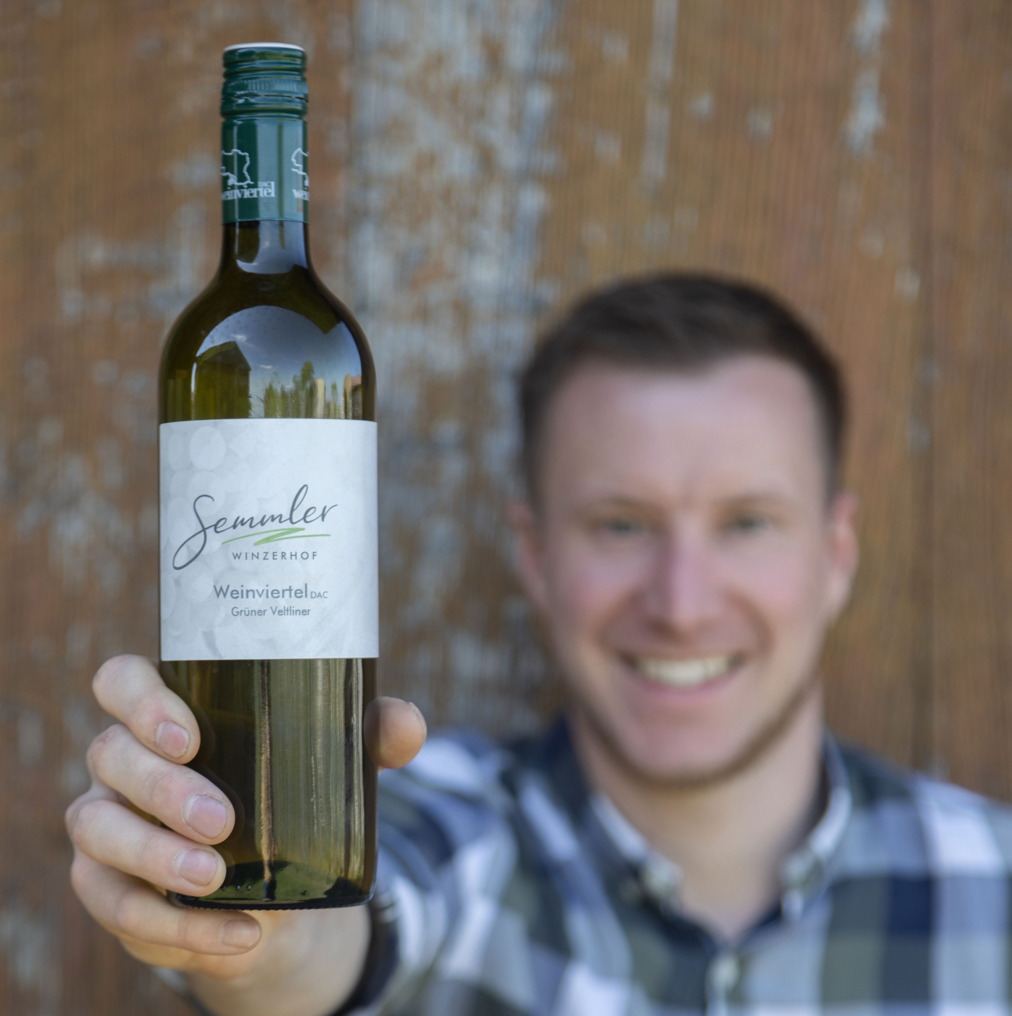 Muž drží pred kamerou fľašu vína Winzerhof Semmler.