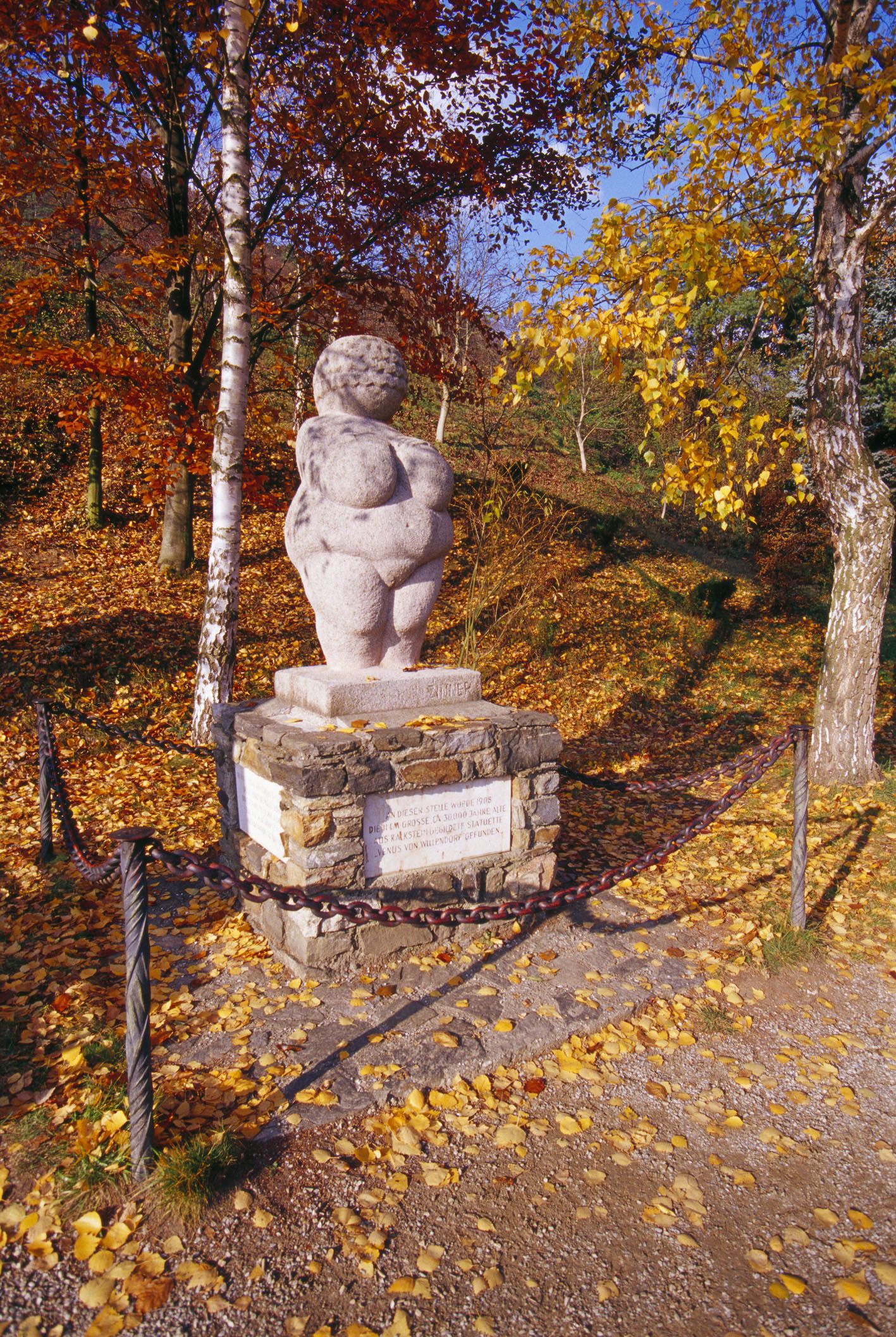 Venuša na podstavci s jesenným lístím okolo nej